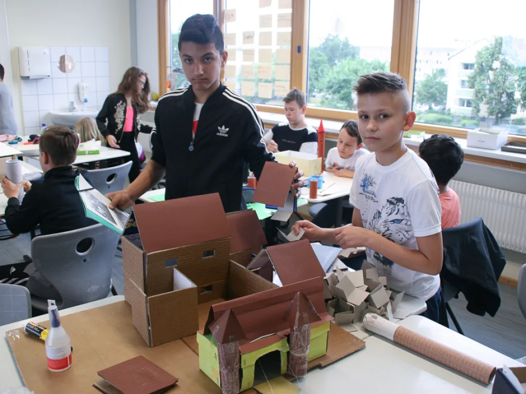 Jugendliche basteln an Modellen aus Pappe.